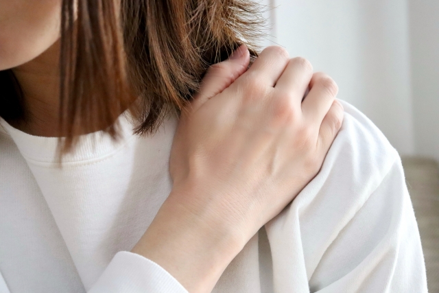 肩こりで肩を抑える女性